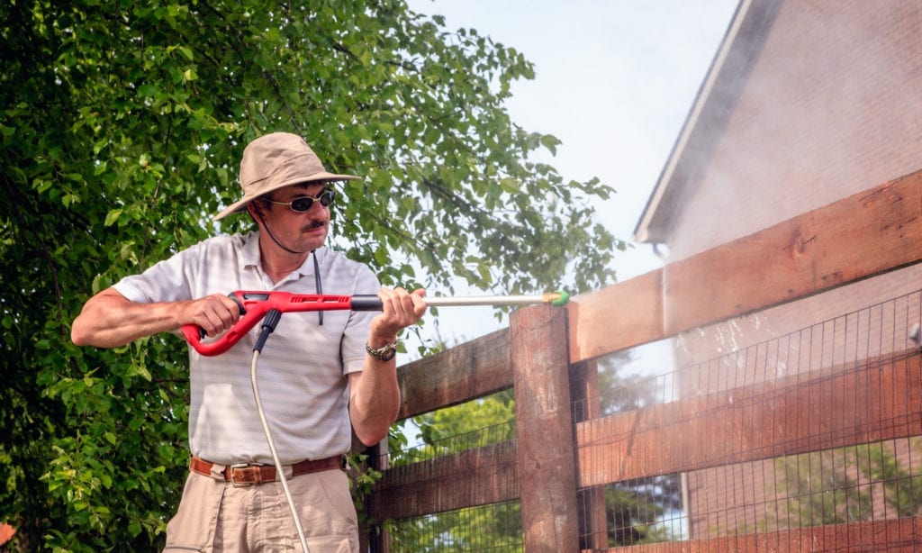 a man jet washing a fence panel