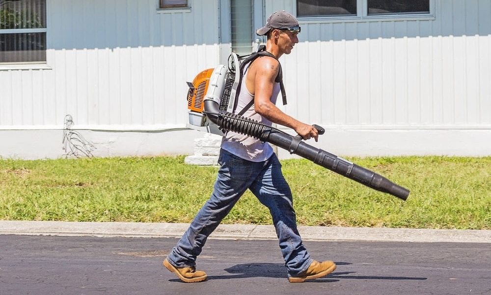 A workman wearing a leaf backpack blower