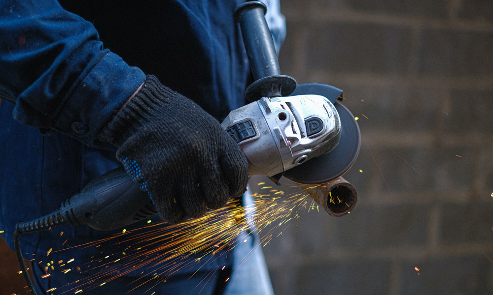 angle grinder cutting metal pole with sparks coming off it