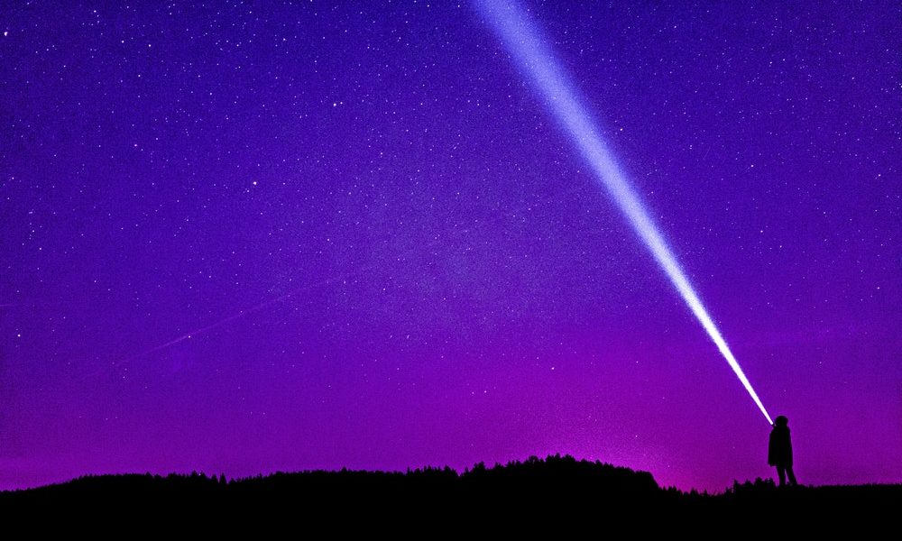 A someone using a Flashlight to look up at the night sky