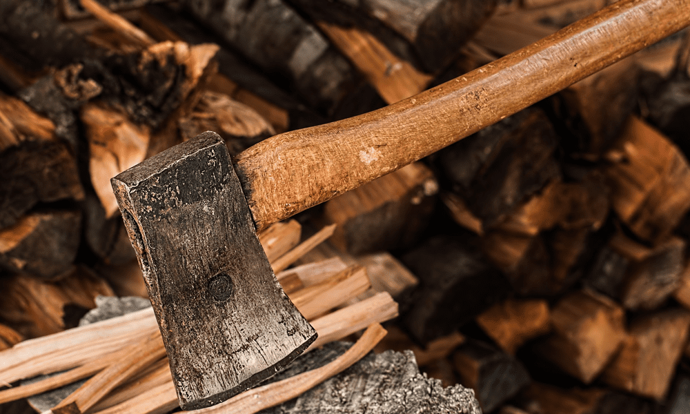 Axe resting on a log with wood in the background