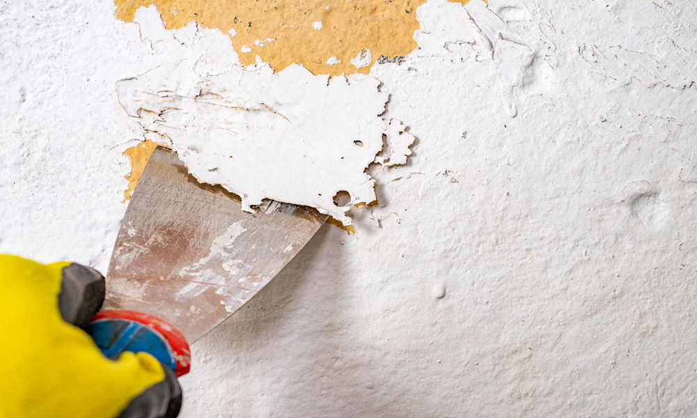 a paint scraper taking paint off a wall