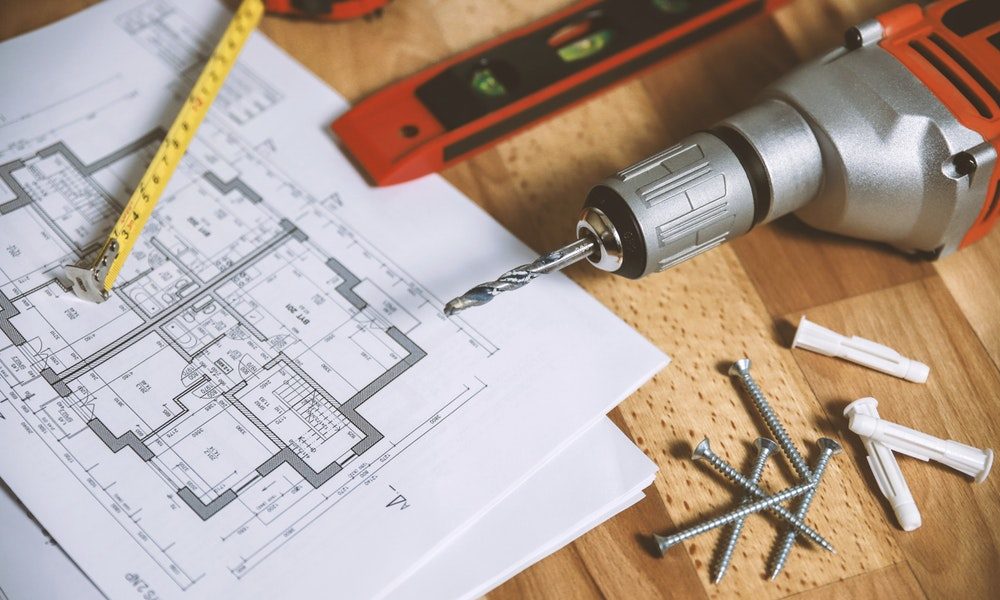 drill, spirit level and tape measure laying on building plans