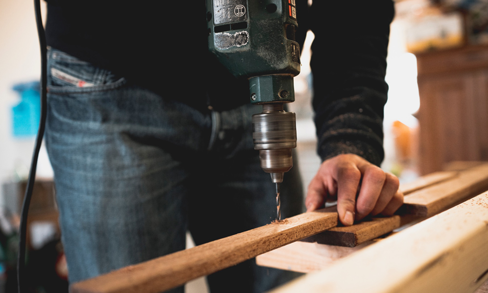 A corded drill, drilling into a piece of wood