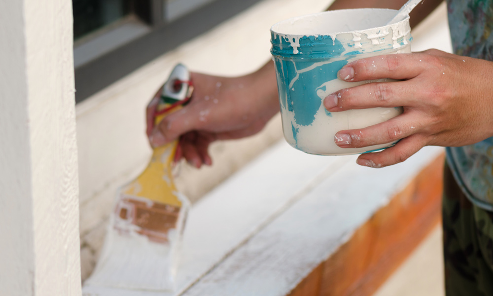 someone painting a outside window ledge