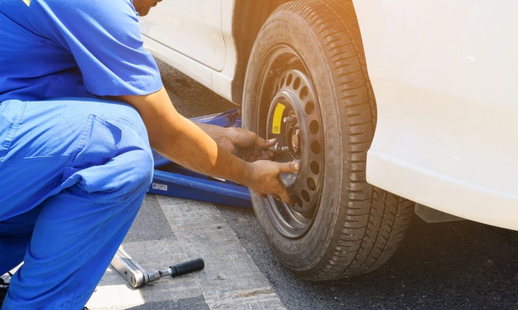 some using a floor jack to change a wheel