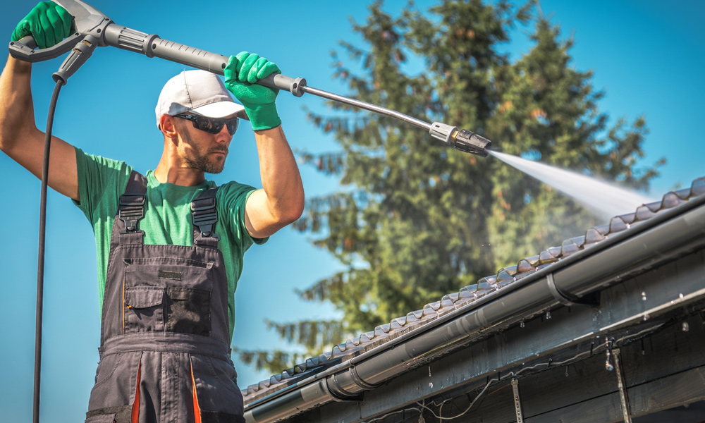 work person jet washing roof tiles