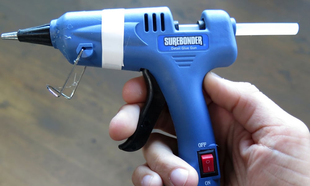 A hand holding a hot glue gun