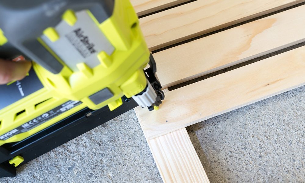 A nail gun nailing a piece of wood