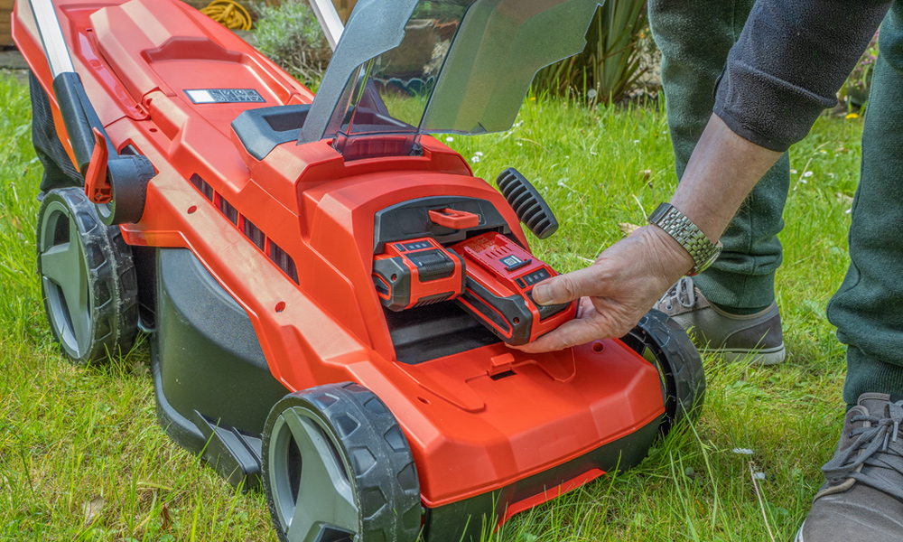 someone loading batteries into an electric lawn mower