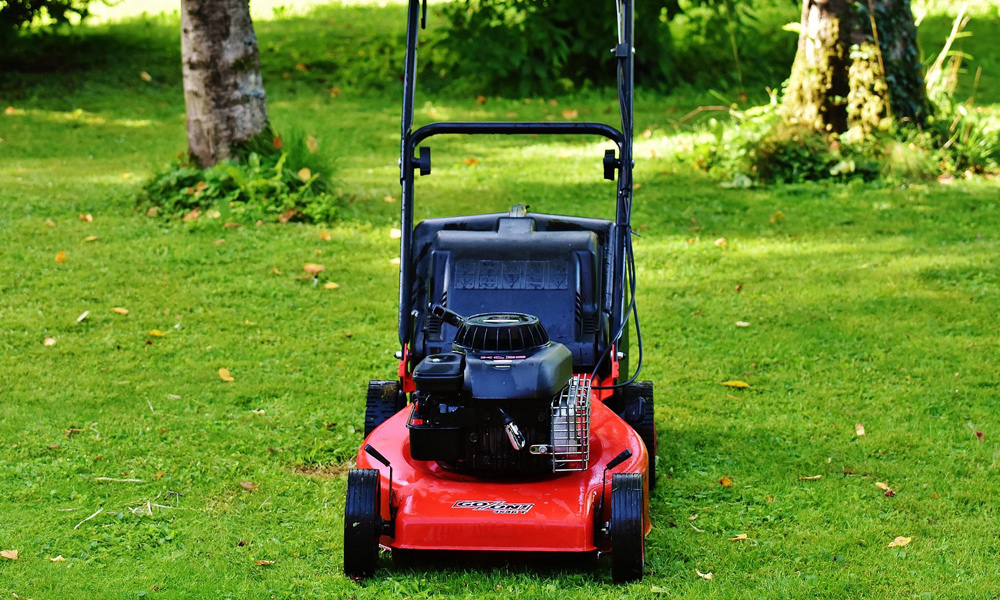 red and black lawn mower sitting on grass