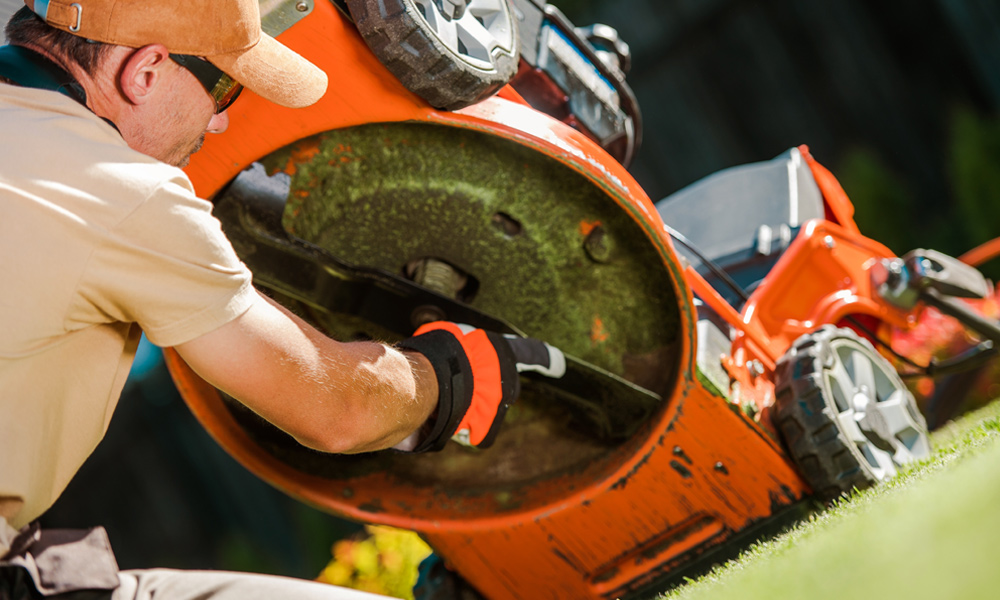 Orange lawn mower on its back with black mower blade