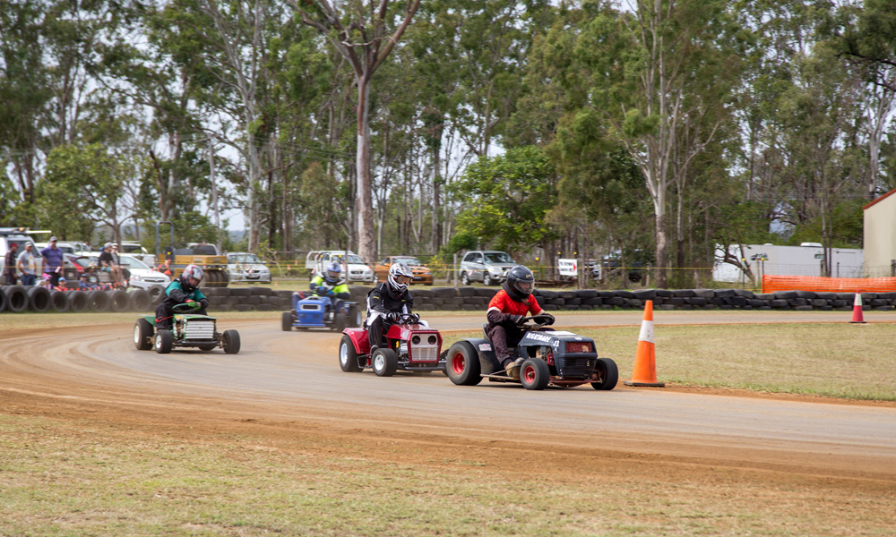 Racing riding lawn mowers going around a track