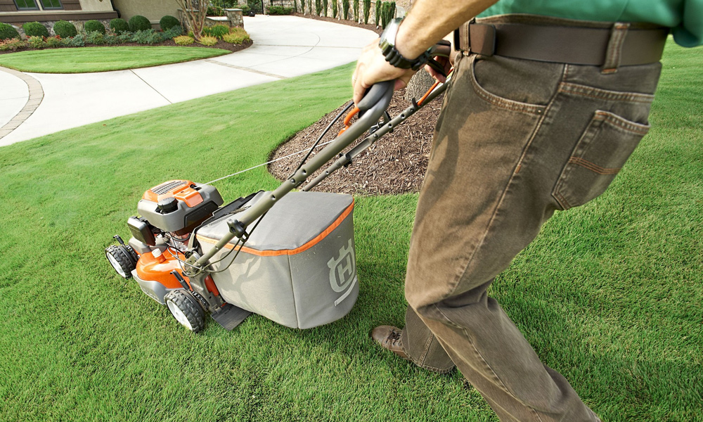 pushing a lawn mower down a grass slope