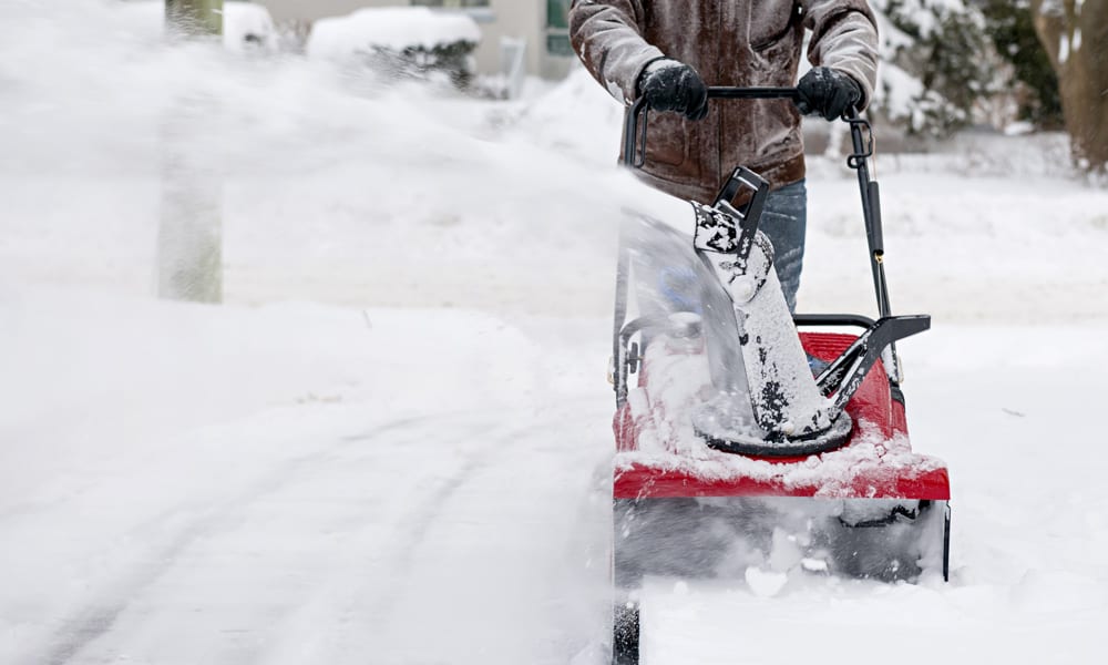 someone pushing a snow blower through snow