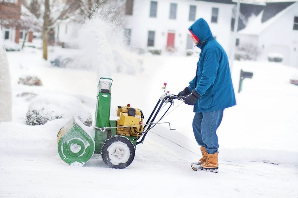 A man using a Snow Blower to clear a pathway