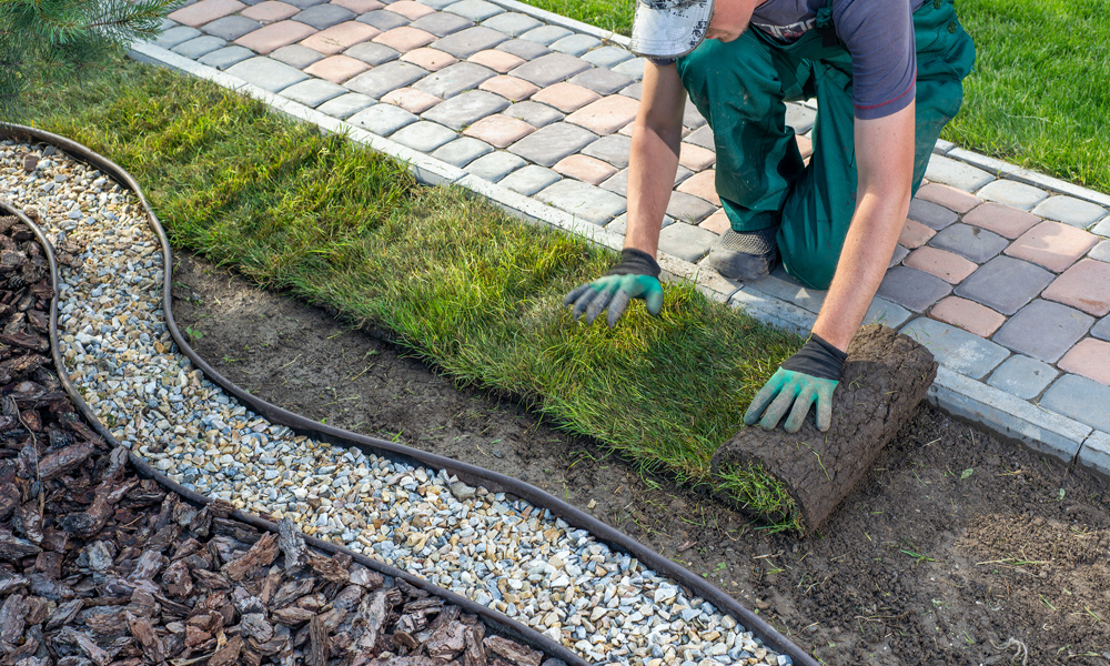 work person rolling out grass turf