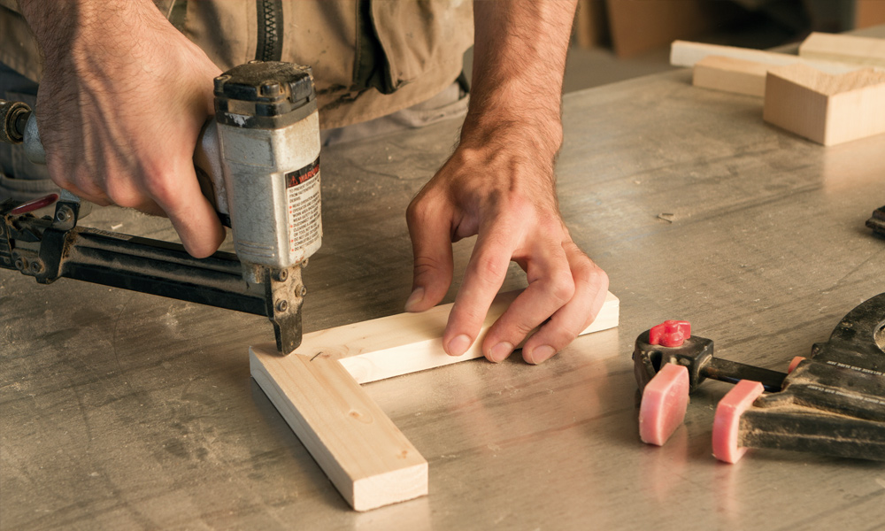 nail gun joining two pieces of wood together 